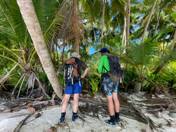 Darryl Birch and Dr Grant Harper with backpacks looking at palm trees
