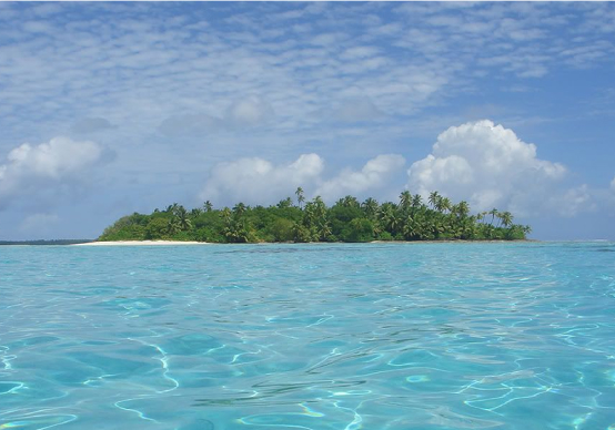 A boat's perspective of Chagos Island, highlighting the vibrant blue waters and expansive sky.
