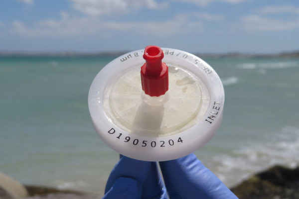 A gloved hand holding a eDNA device